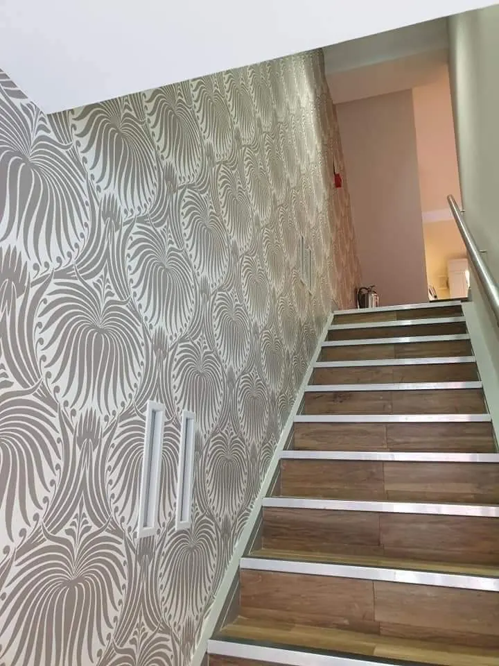 Staircase painted sage green with patterned wallpaper